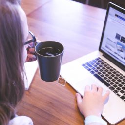 woman working on a mac laptop with a cup of tea