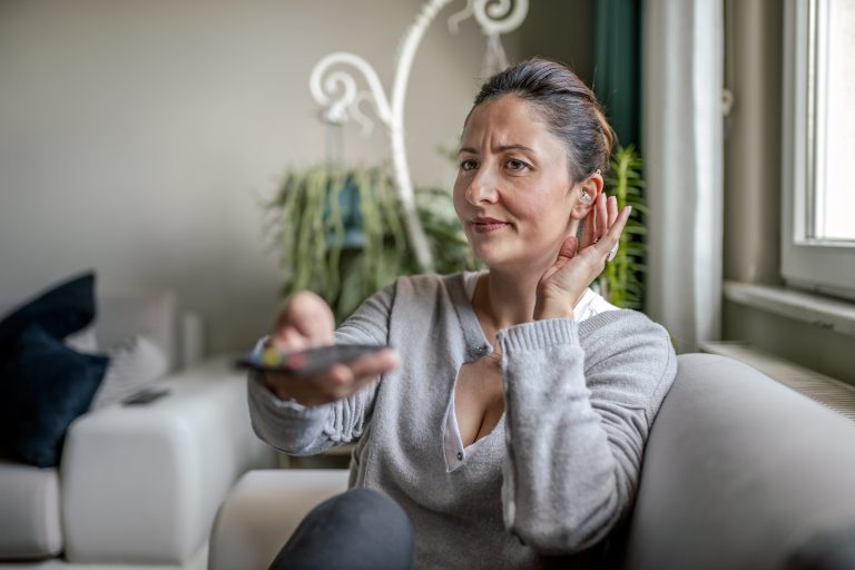woman-hearing aid-tv Woman with hearing aid watching television