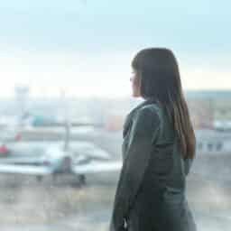 Woman standing outside an airport looking at a plane.