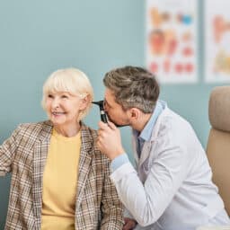 Smiling senior woman receiving an ear exam.