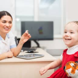Audiologist explaining hearing aids to smiling young girl