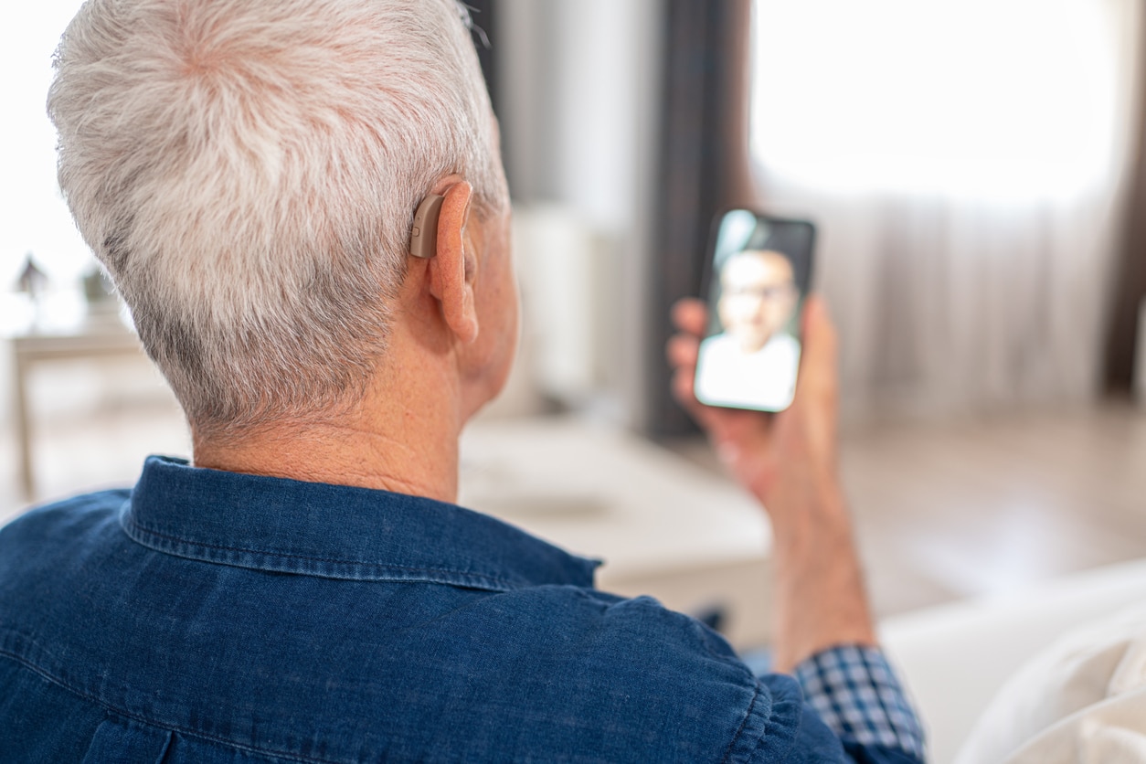 Man video calling through a hearing aid.