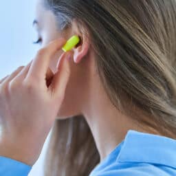 Young brunette woman using earplugs for noise protection