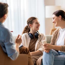 Happy family of three chatting in the living room.