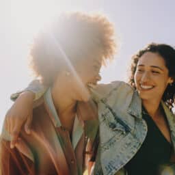 Two best friends laughing and enjoying each other's company on a summer's day in the park. Happiness and friendship in a natural outdoor setting.