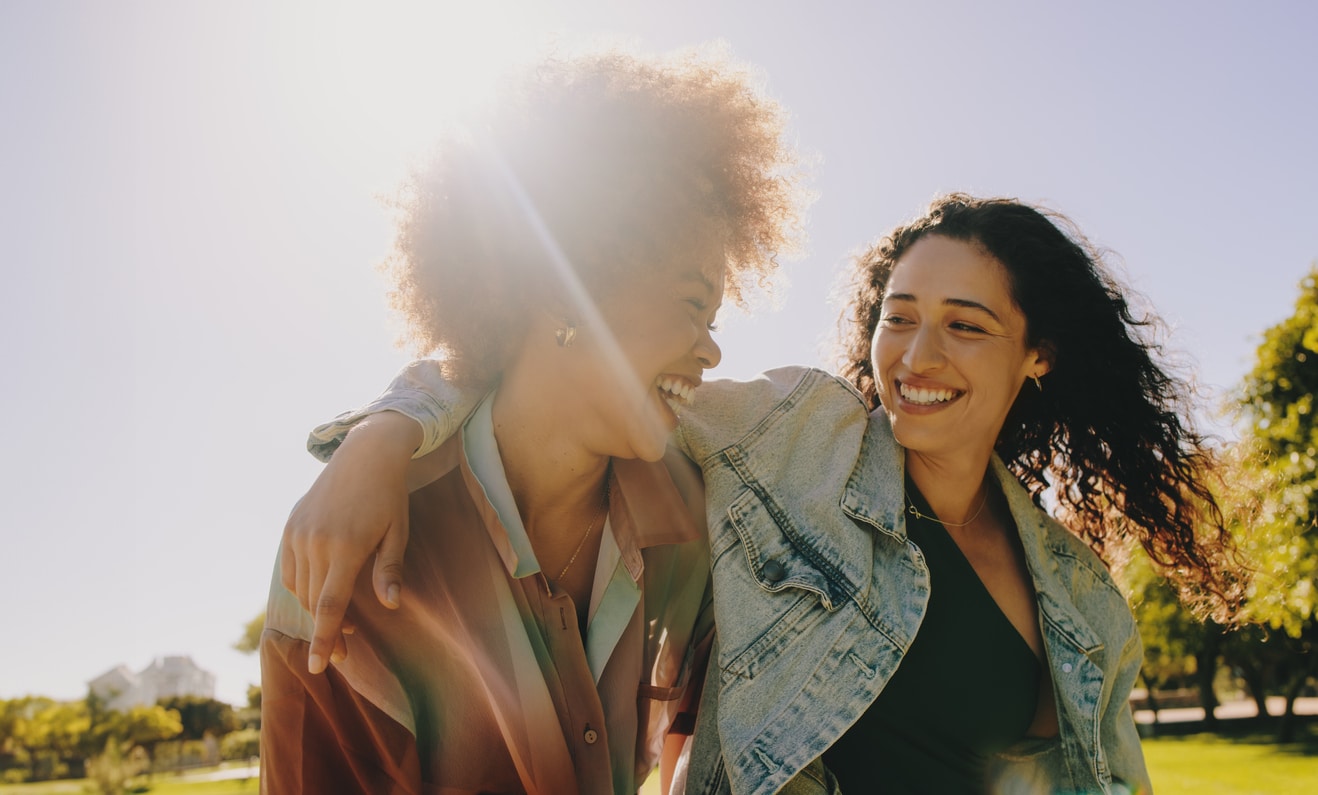 Two best friends laughing and enjoying each other's company on a summer's day in the park. Happiness and friendship in a natural outdoor setting.